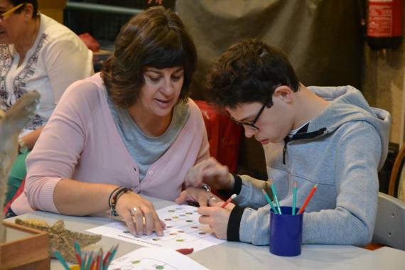 Una mujer ayudando a un niño con TEA a hacer una actividad del MNCN